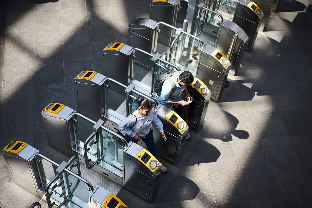 Travelers check in at entrance gates at a train station.